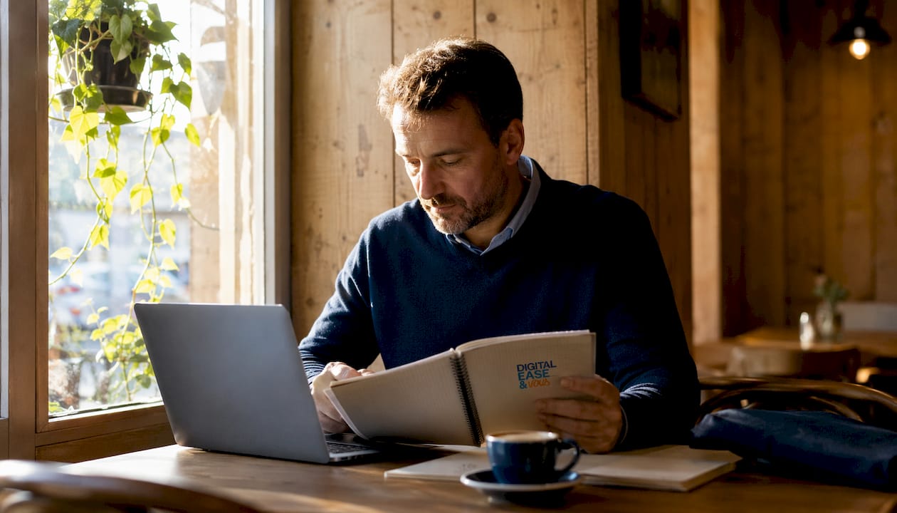 Un homme plongé dans ses pensées, assis dans le bureau épuré d’une petite entreprise.