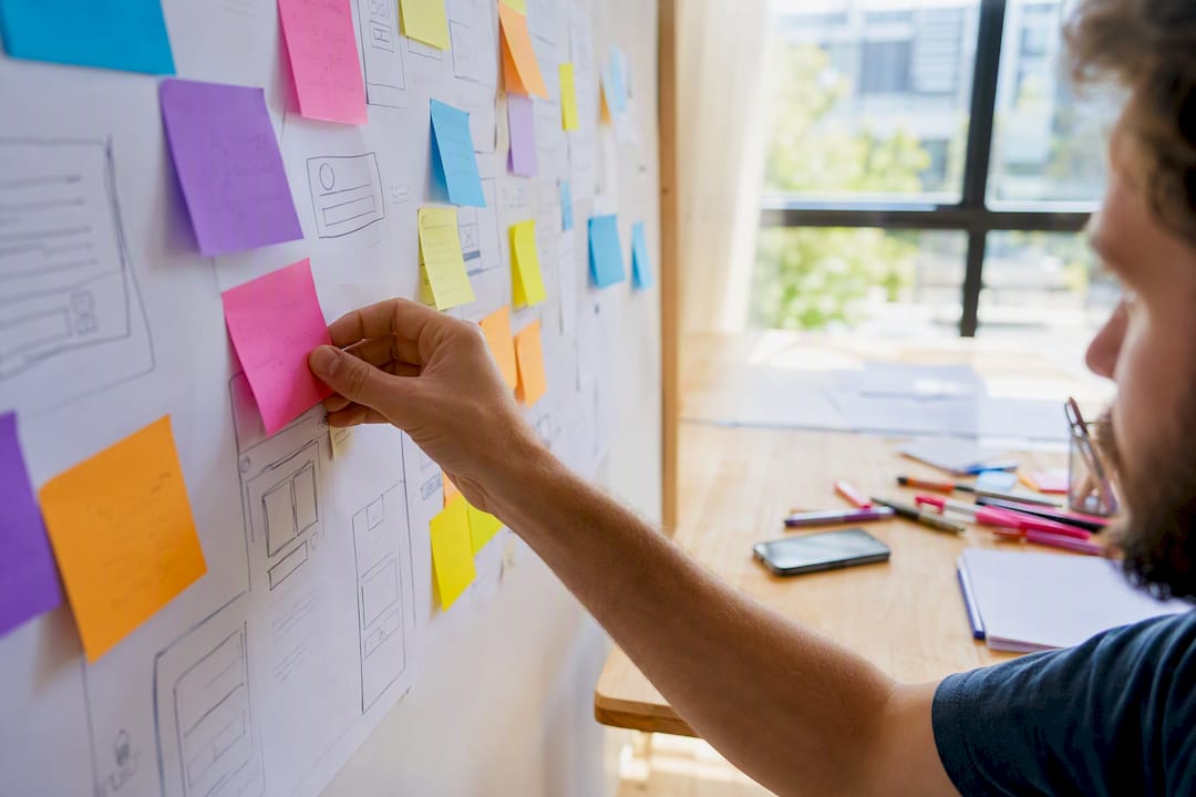 Déployer un CRM en entreprise : les étapes qui garantissent le succès 3 Une main colle un post-it sur une carte du parcours client.