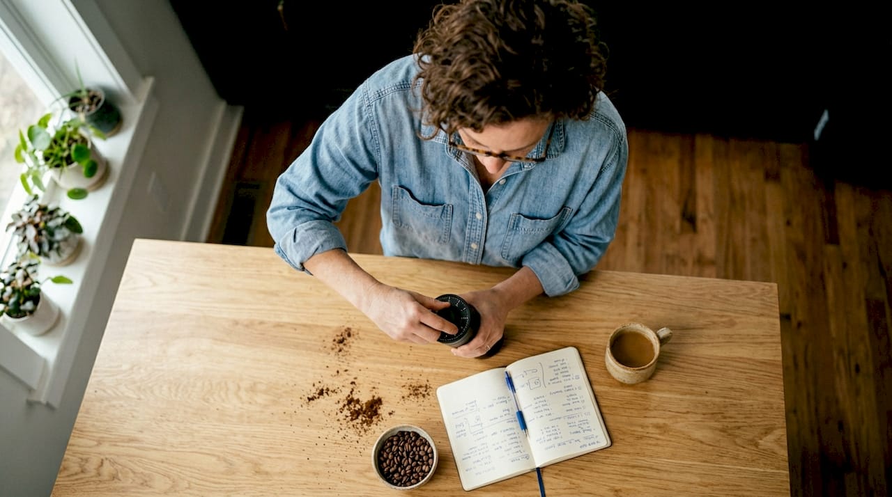 Woman adjusting burr grinder at home table