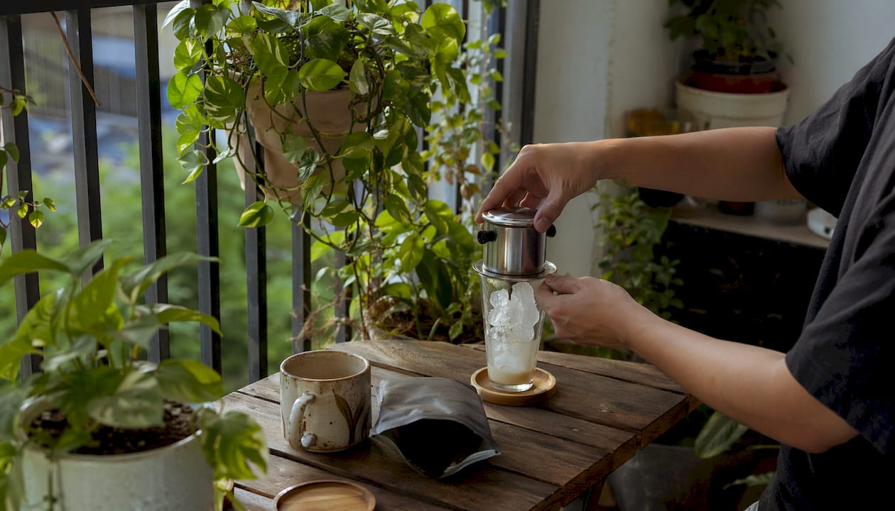Hands brewing Vietnamese iced coffee with metal drip filter