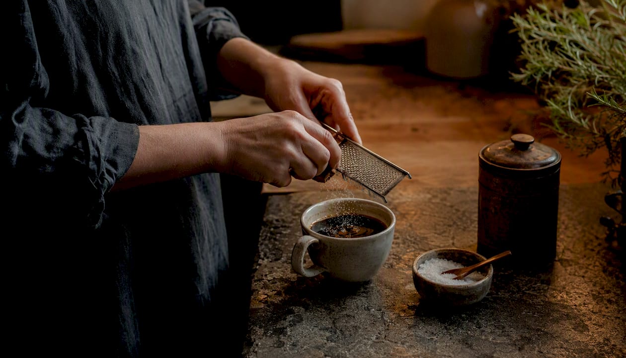 Adding cinnamon spice to coffee outdoors
