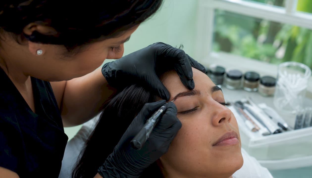 Detalle en primer plano del proceso de microblading y aplicación de henna en las cejas