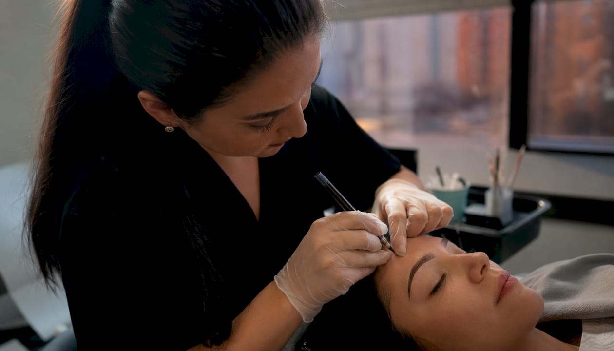 Detalle de unas manos realizando la técnica de microshading en las cejas