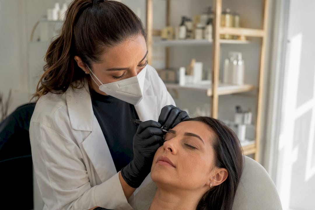 Técnico realizando microblading con trazos finos en cejas