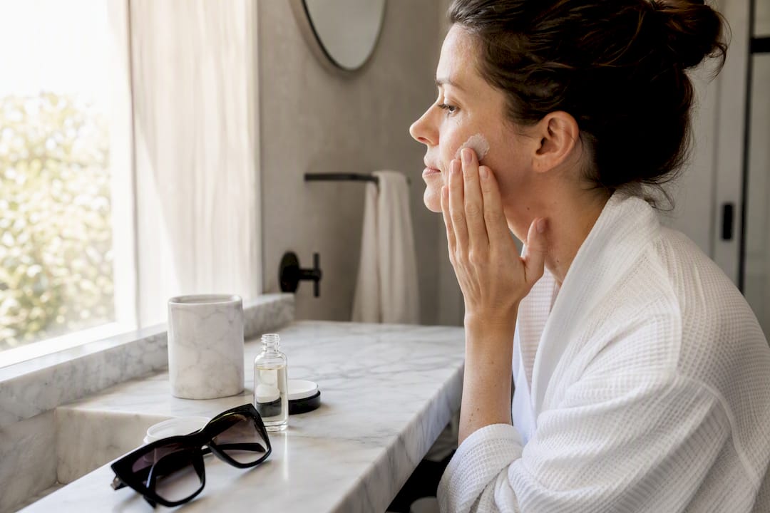 Mujer aplicándose protector solar en el rostro después del peeling