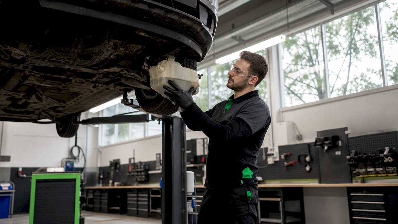 Technician draining engine oil during depollution