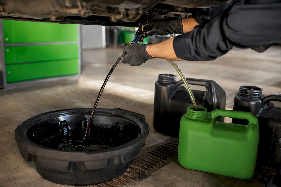 Technician draining vehicle fluids for recycling