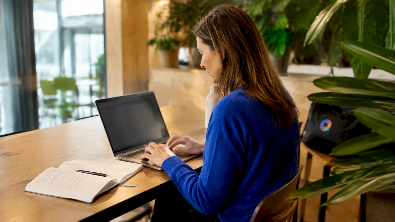 Les mains d’une femme tapent une requête d’intelligence artificielle sur son clavier.