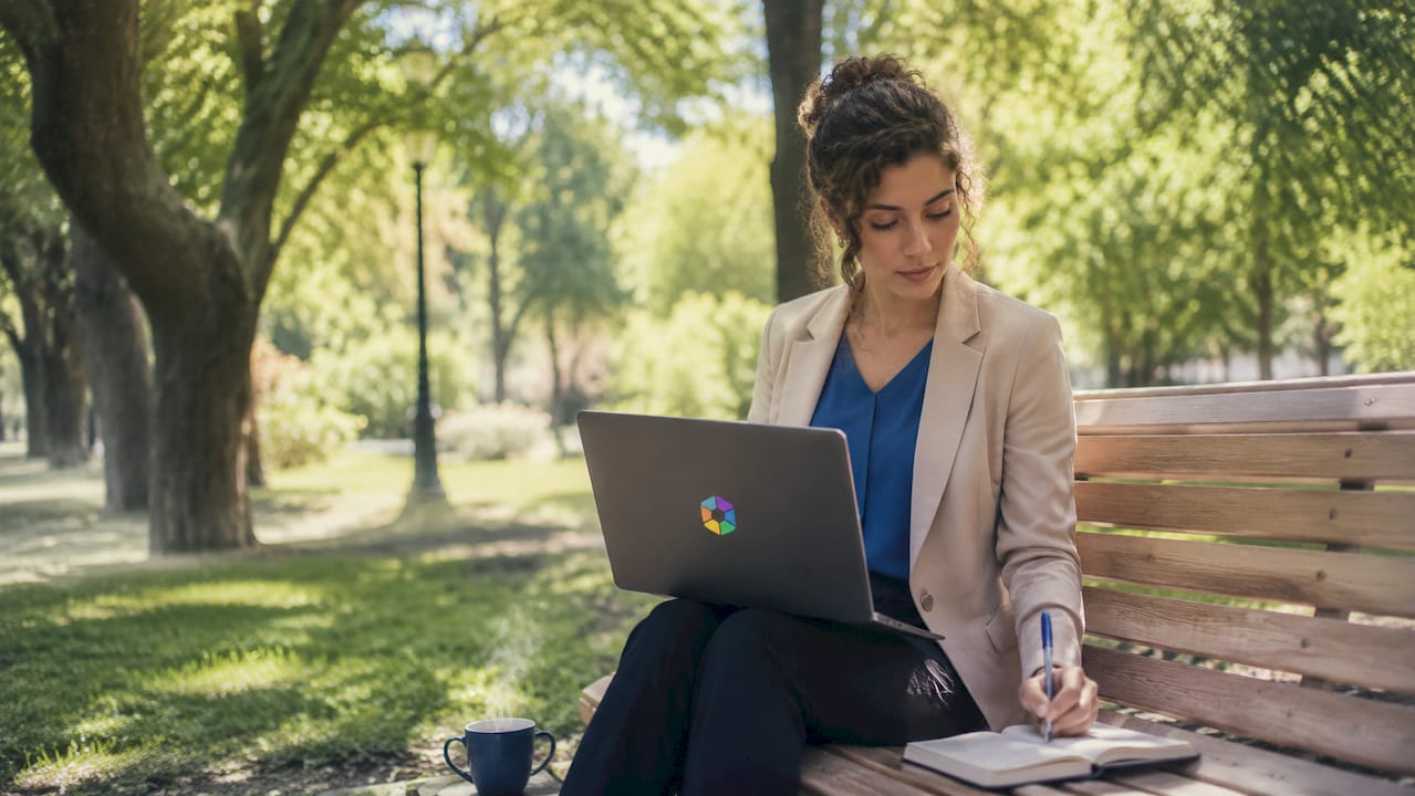 Une femme travaille sur son ordinateur portable dans un café, profitant des outils d’intelligence artificielle pour avancer sur ses projets.