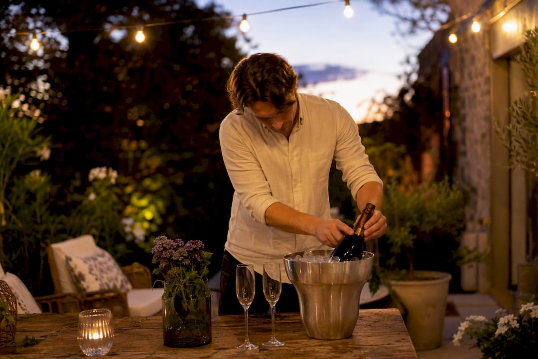 Host placing sparkling wine in ice bucket