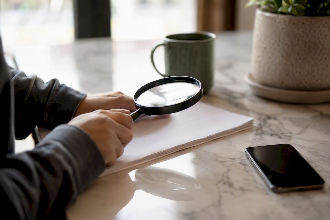 Hands examining insurance details with magnifying glass