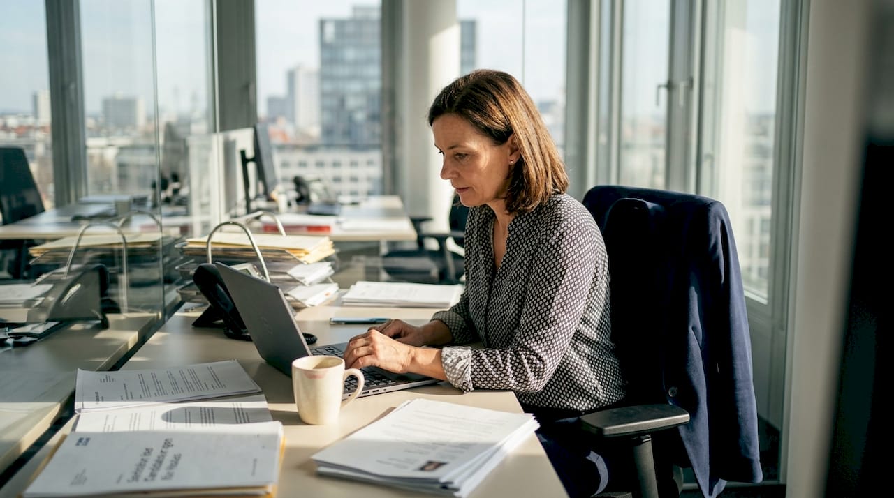 Inmitten des geschäftigen Büroalltags prüft die HR-Managerin sorgfältig die Bewerbungsunterlagen der Kandidaten und entscheidet, wer zum Vorstellungsgespräch eingeladen wird.