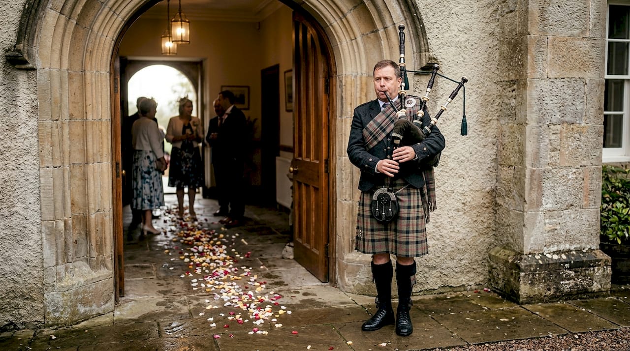 Bagpiper greeting guests at wedding entrance