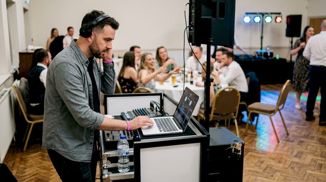 Wedding DJ mixing music at busy reception