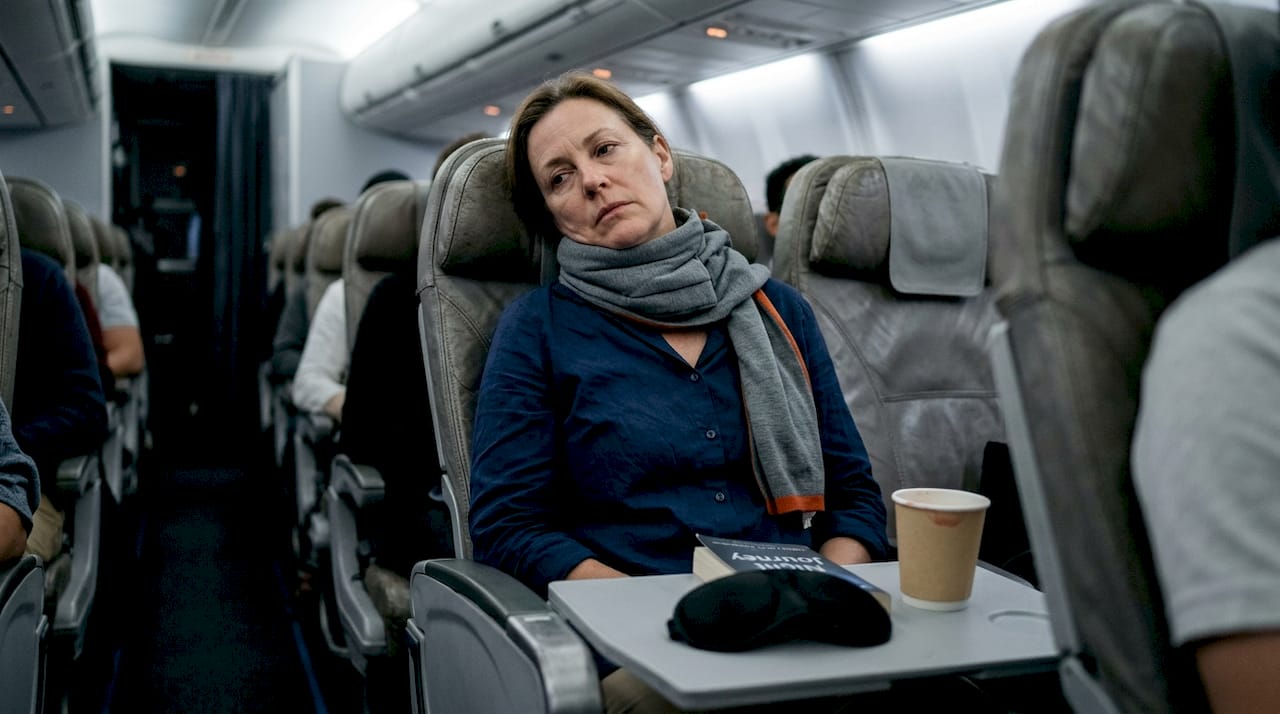 Traveler using neck pillow for upright sleep