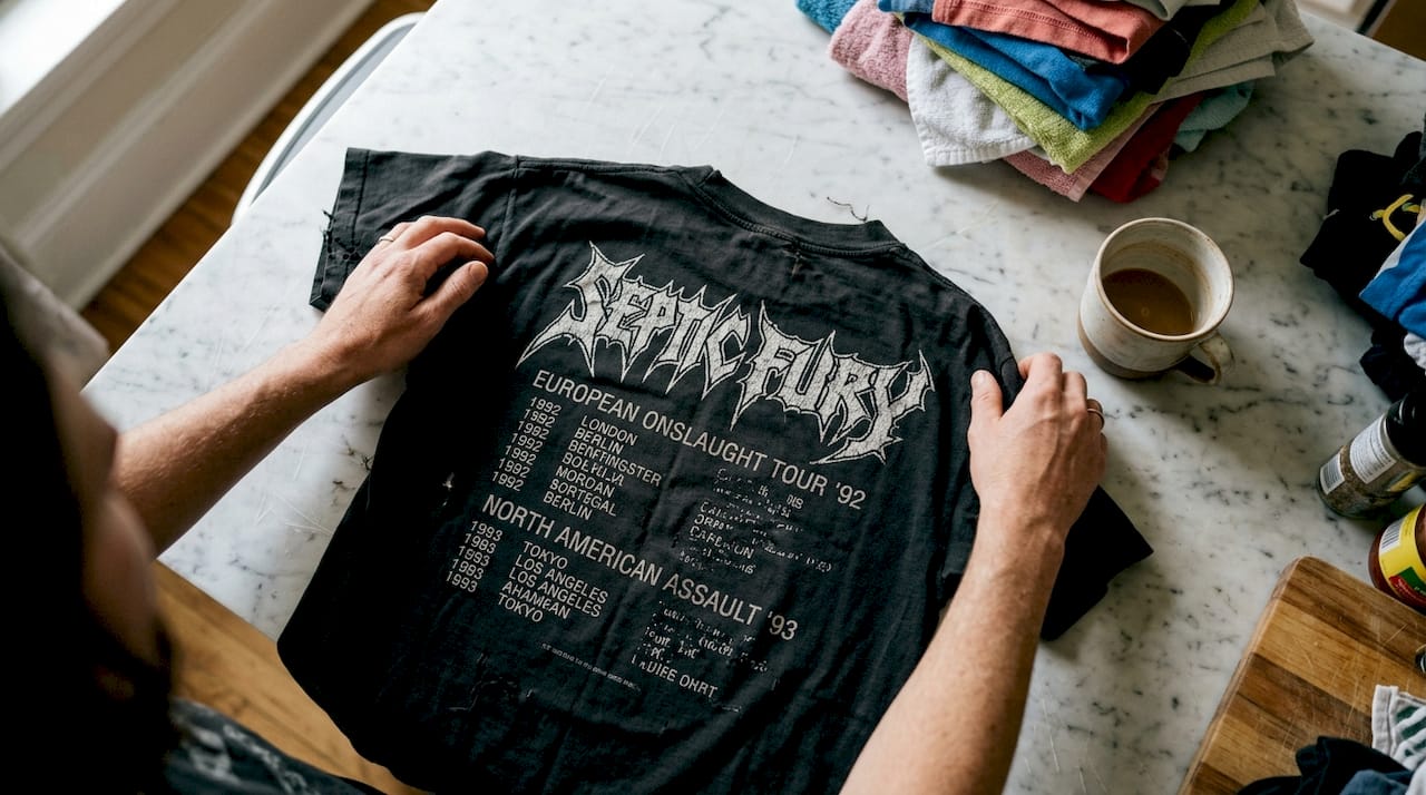Hands holding worn thrash metal band tee