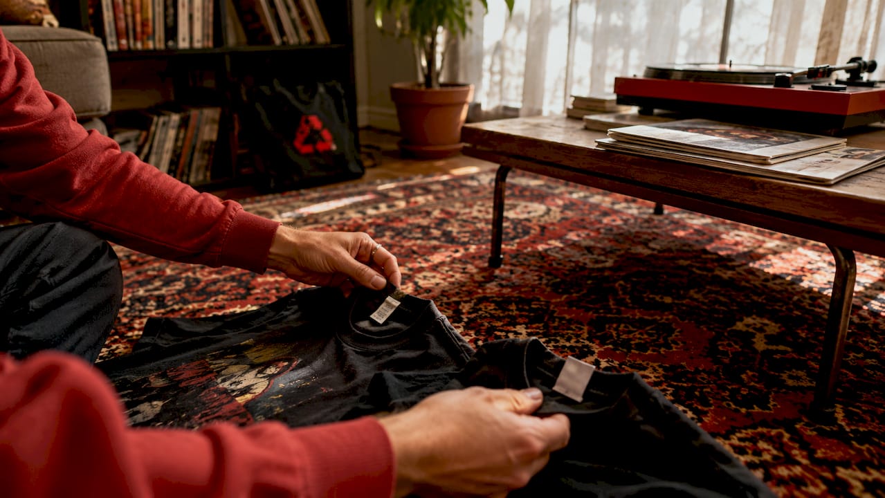 Hands comparing authentic and bootleg merch tags