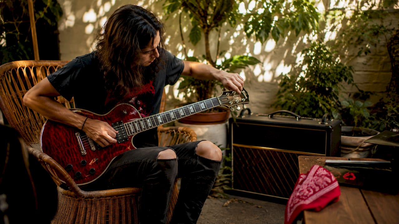Hands tuning electric guitars in rehearsal room
