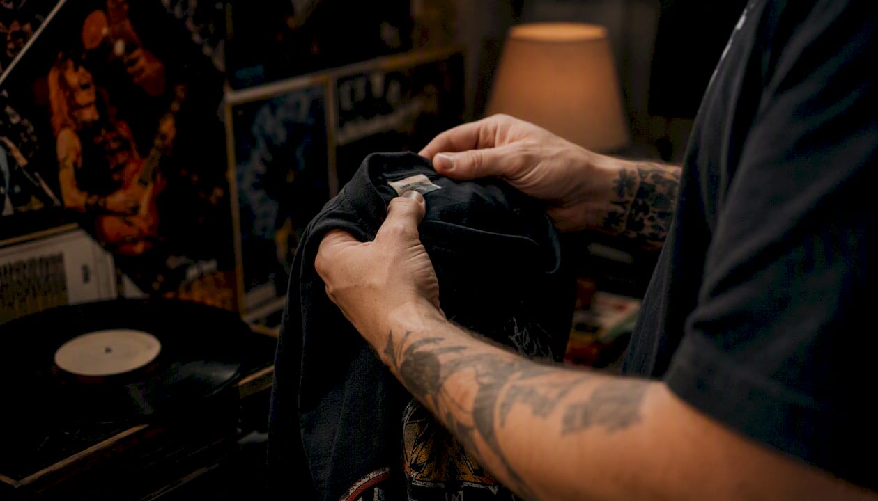 Hands inspecting vintage metal shirt print and tag