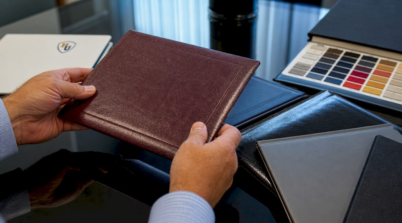 Hands examining diploma cover materials