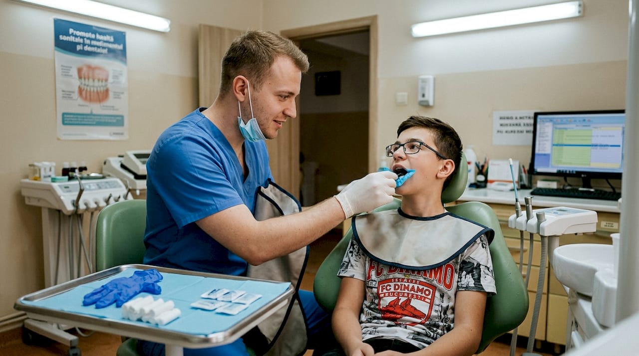 Asistenta stomatologică pregătește pacientul pentru efectuarea unei radiografii intraorale.