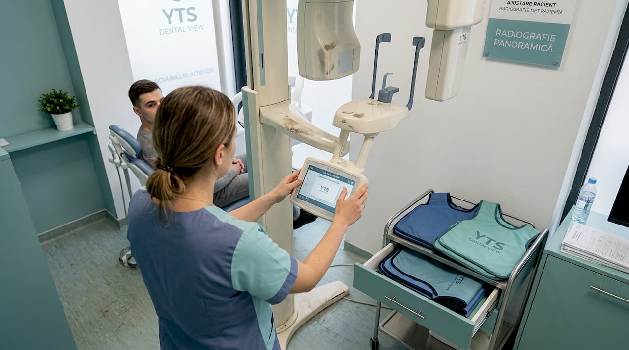 Tehnicianul reglează aparatul digital pentru radiografii dentare.