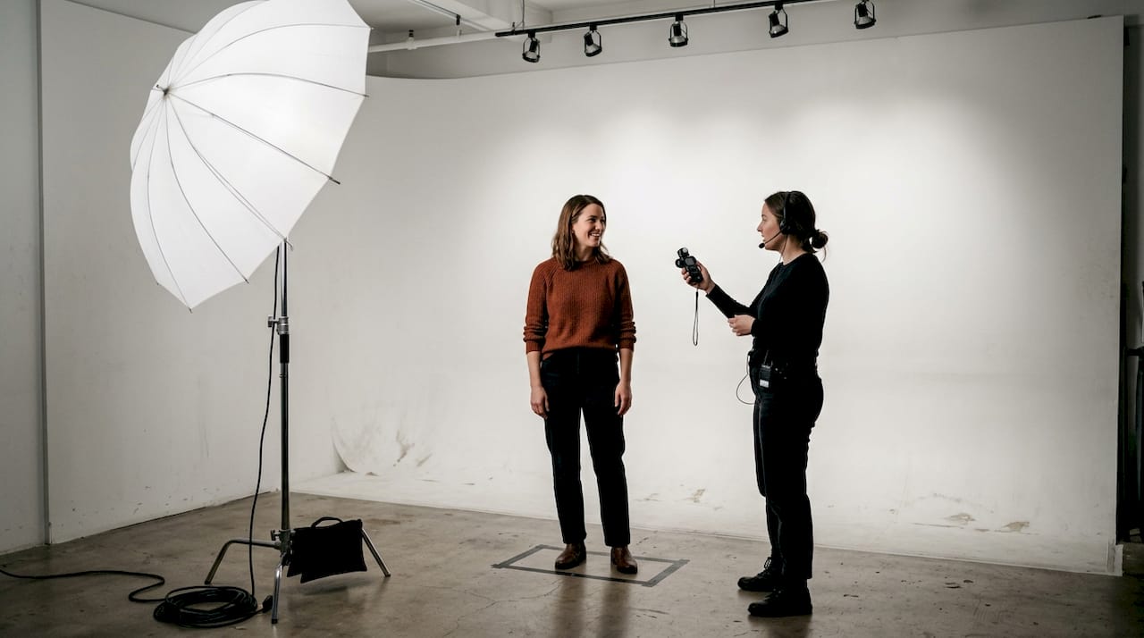 Subject interacting with assistant on large backdrop