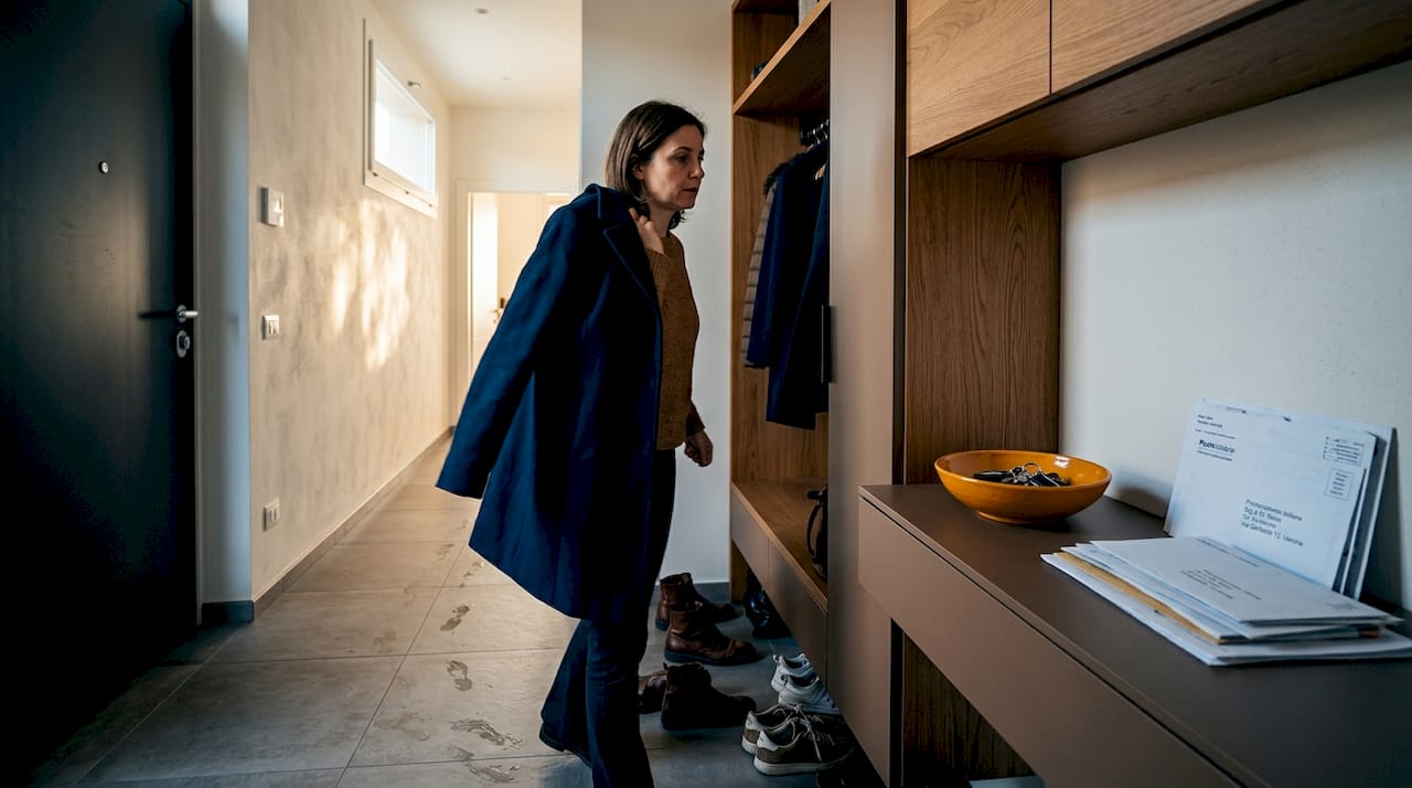 Una donna varca la soglia di un ingresso moderno, pensato per essere funzionale e accogliente.