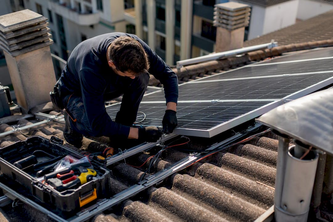 Tecnico che installa pannelli solari sul tetto di un condominio