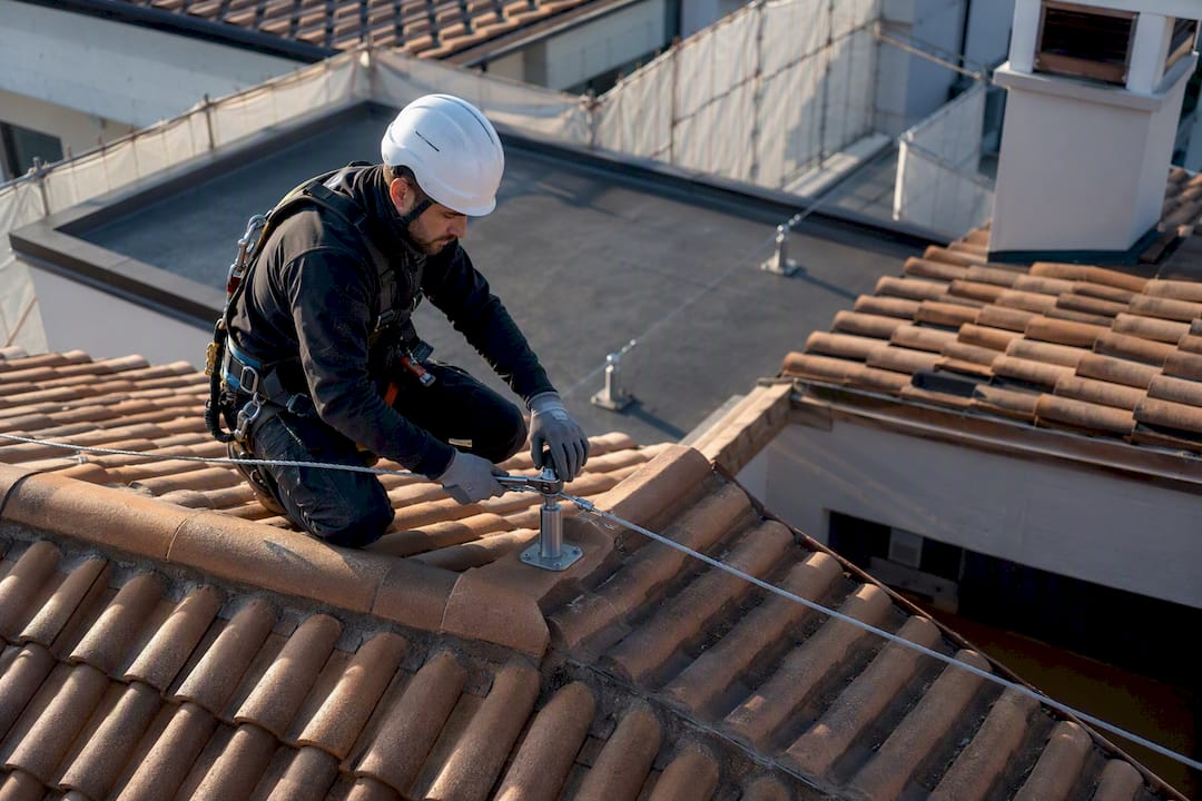 Tecnico installa linea vita su tetto complesso