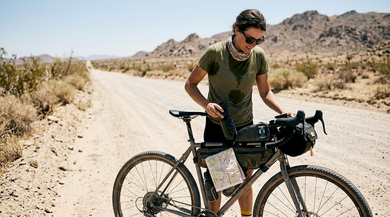 Cyclist adjusting water bottle in desert setting