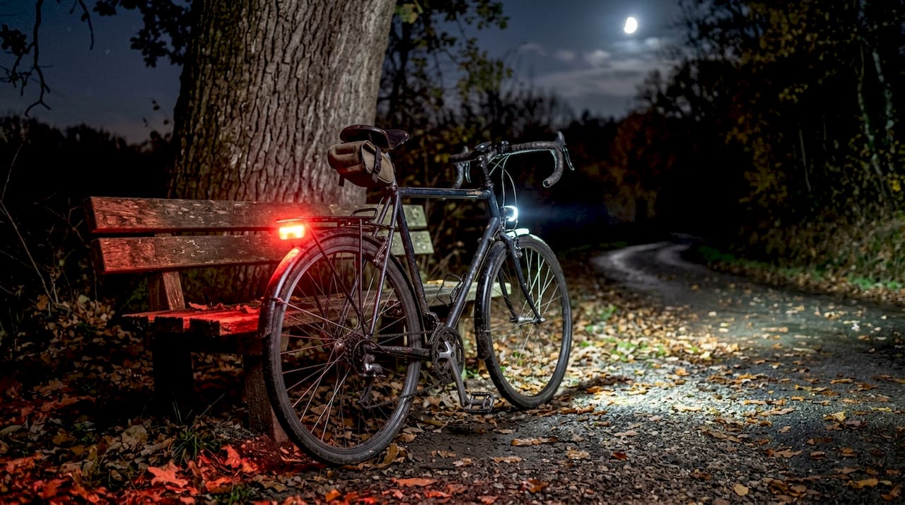 Gros plan sur les éclairages avant et arrière d’un vélo allumés.