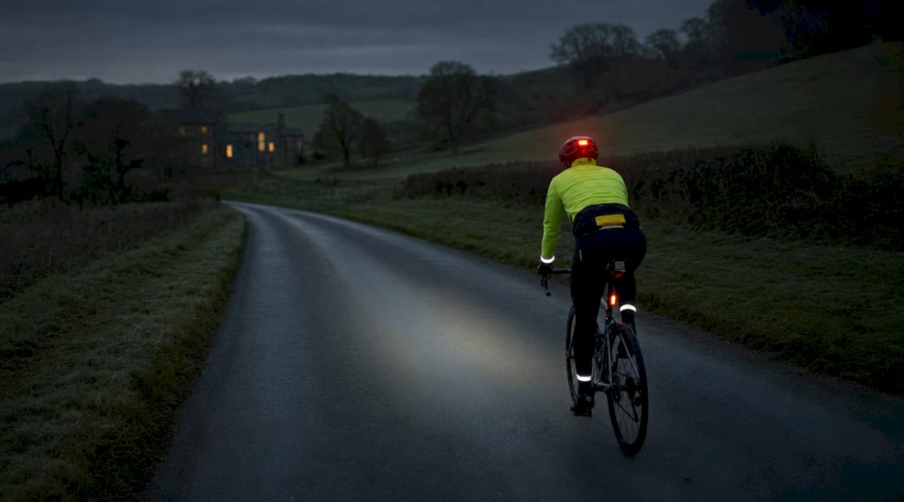 Cyclist riding with layered visibility gear at twilight