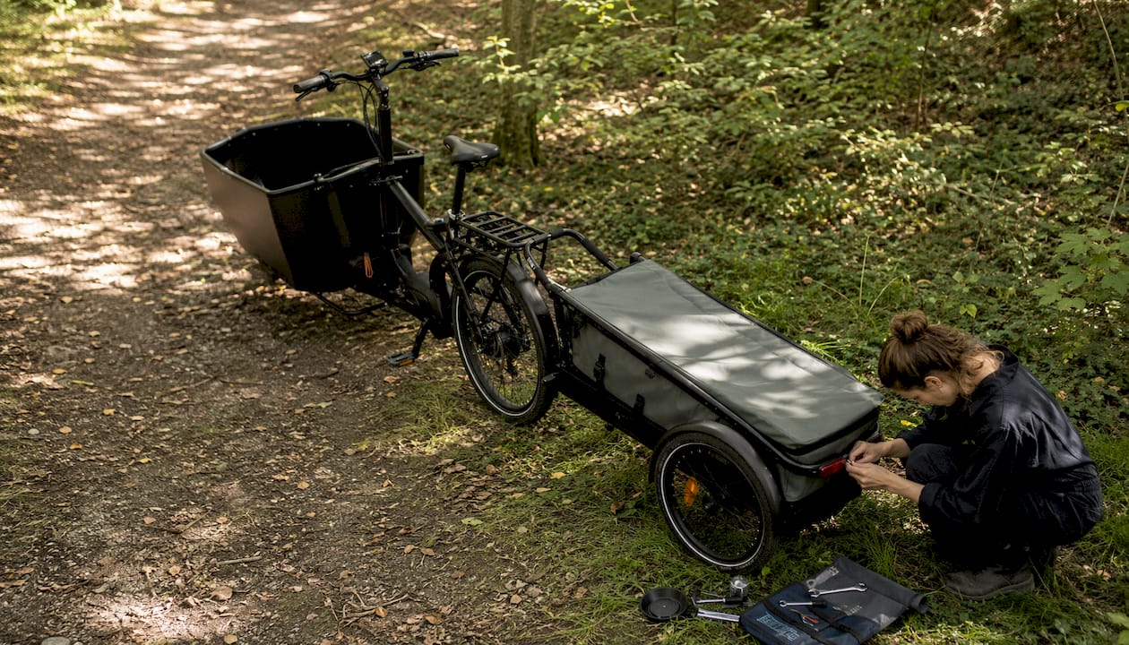 Un mécanicien installe un catadioptre sur une remorque de vélo cargo.