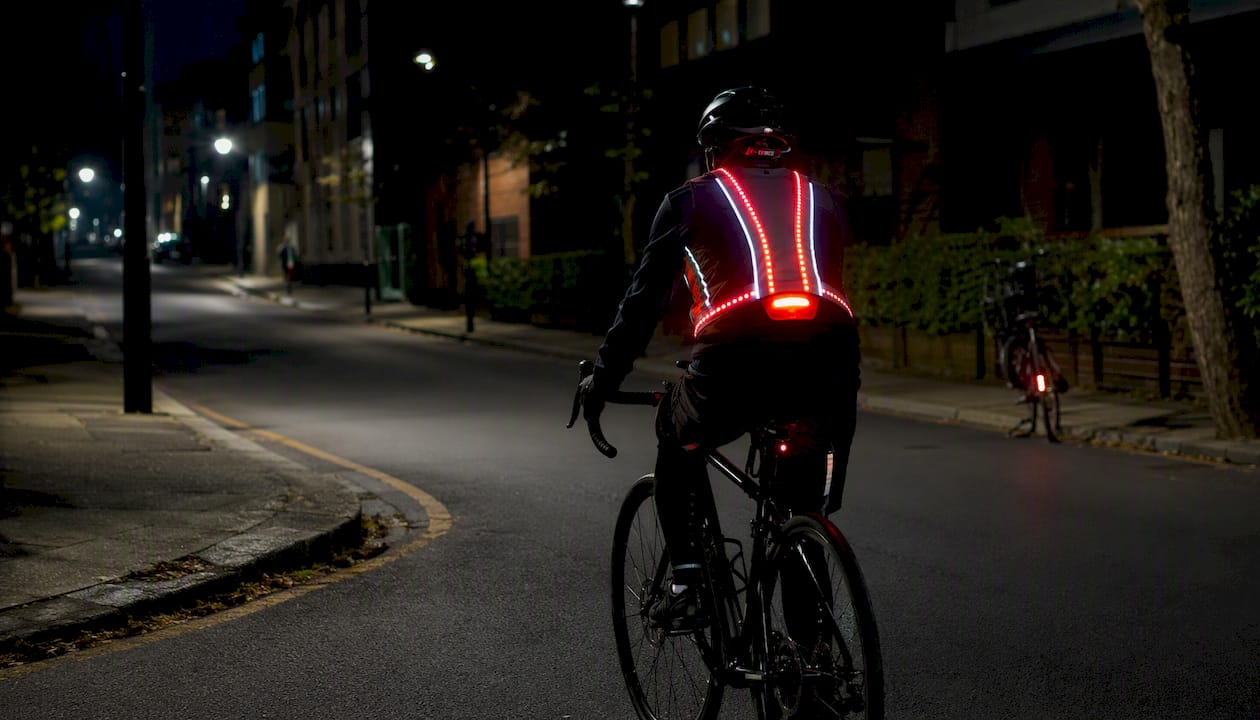 Cyclist adjusting LED illuminated vest at night