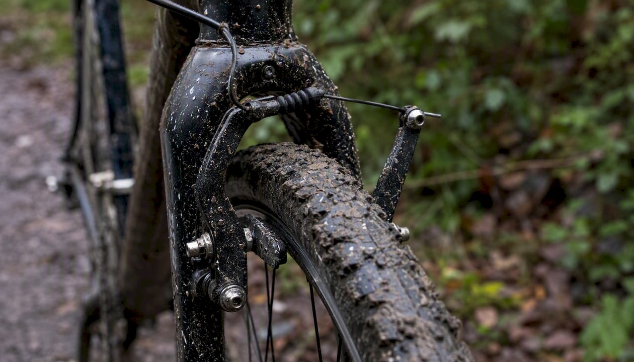 Des freins cantilever en pleine action sur une roue de cyclocross couverte de boue