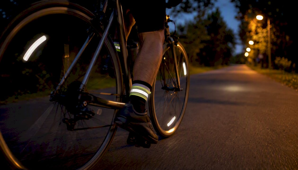 Des bandes réfléchissantes autour des chevilles et sur les rayons du vélo à la tombée de la nuit