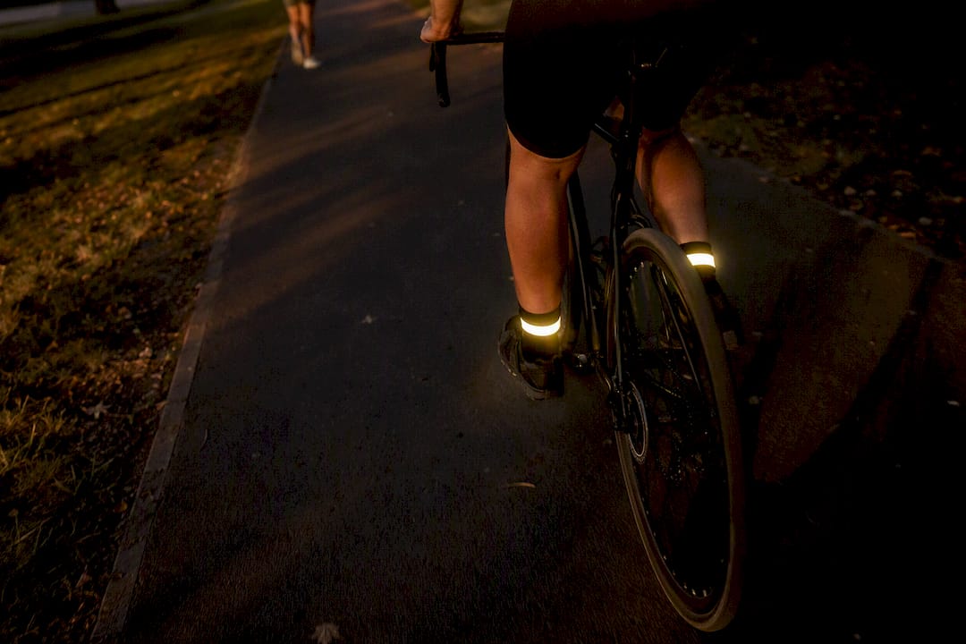 Reflective ankle bands glowing on cyclist's moving feet