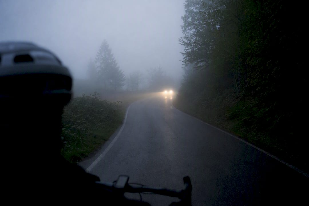 Foggy road with diffused headlights at dawn