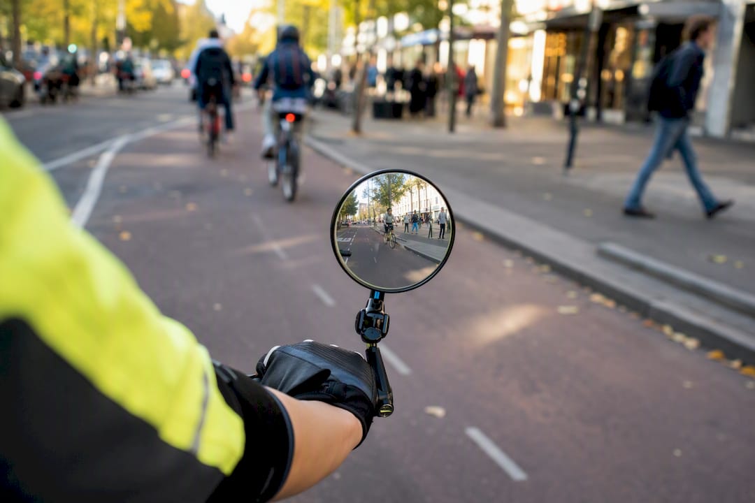 Rearview mirror reflecting urban traffic behind cyclist
