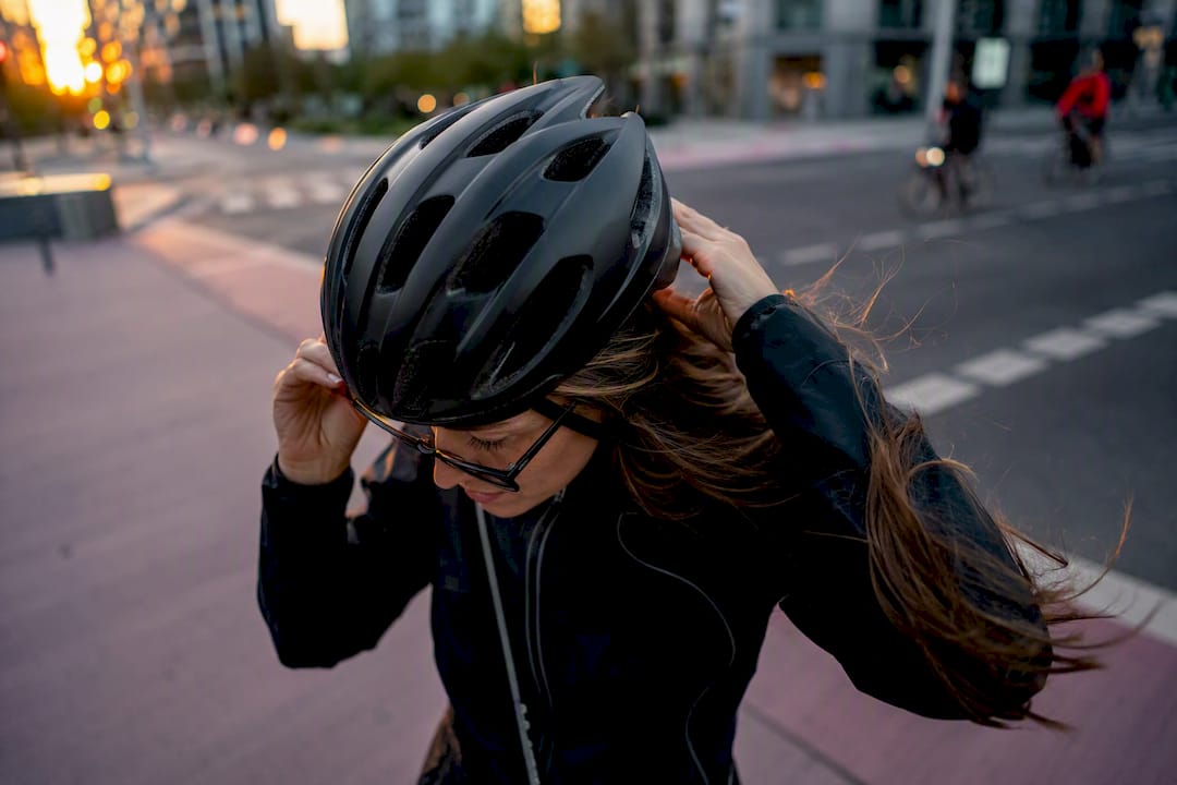 Cycliste aux lunettes et aux cheveux longs ajustant son casque
