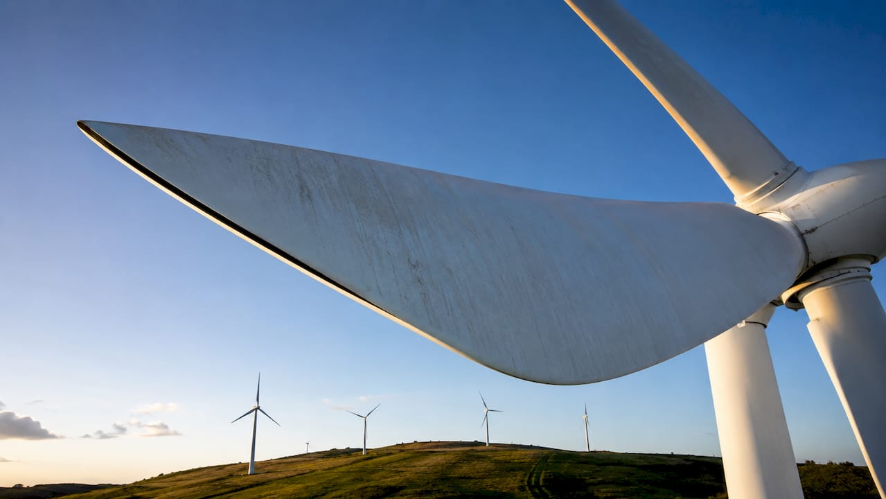 Nahaufnahme der Rotorblätter einer Windkraftanlage vor blauem Himmel