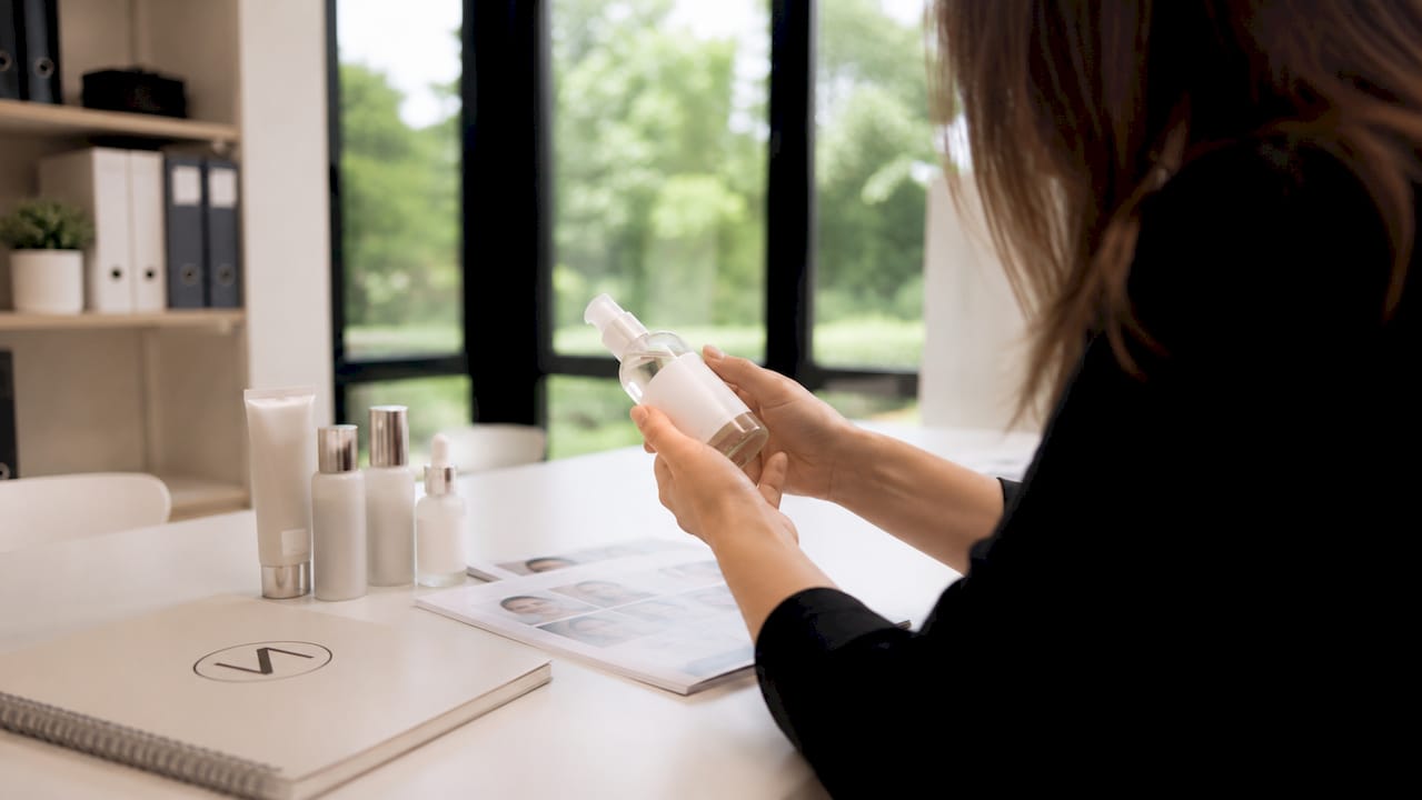 Studiennachweise in der Kosmetik 2 Ein Paar Hände hält ein Kosmetikprodukt und betrachtet aufmerksam das Etikett.