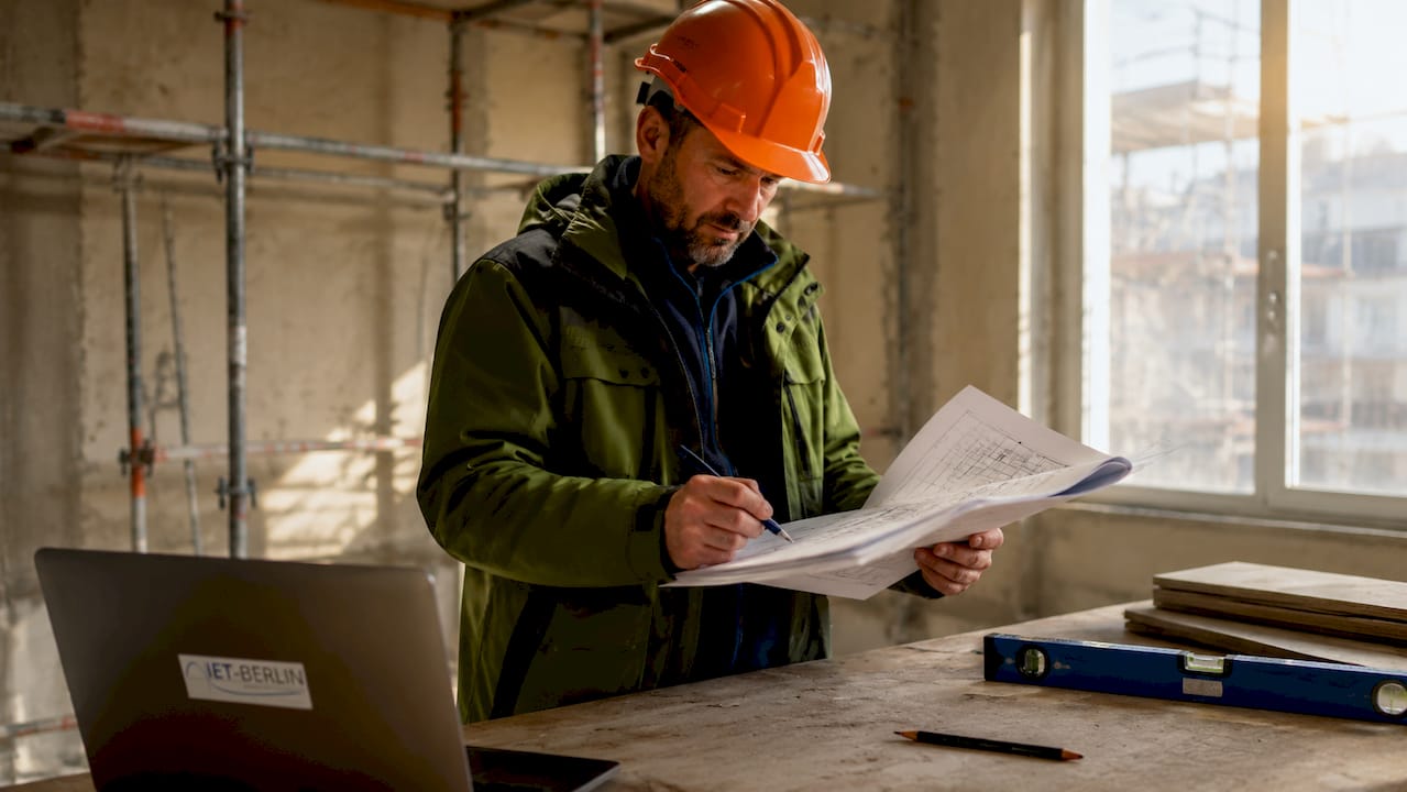 Fachmann begutachtet die Baustelle und überprüft die Unterlagen.