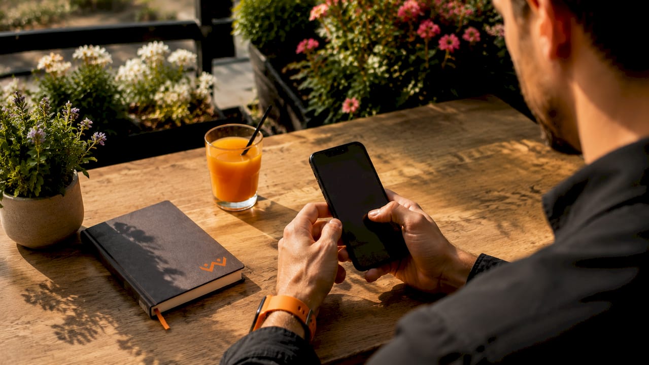 Eine Person scrollt entspannt mit einer Hand am Smartphone, während sie im Café sitzt.