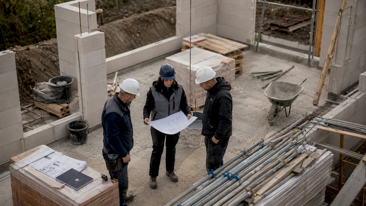 Die Bauleiterin stimmt sich direkt vor Ort mit dem Team über die nächsten Schritte auf der Baustelle ab.