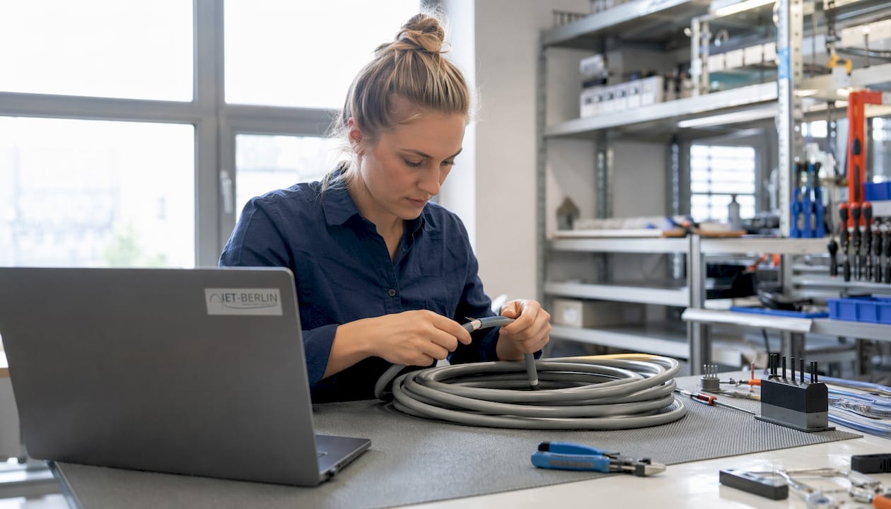 Ein Techniker überprüft die Stromkabel auf der Kabeltrasse mit Messgeräten.