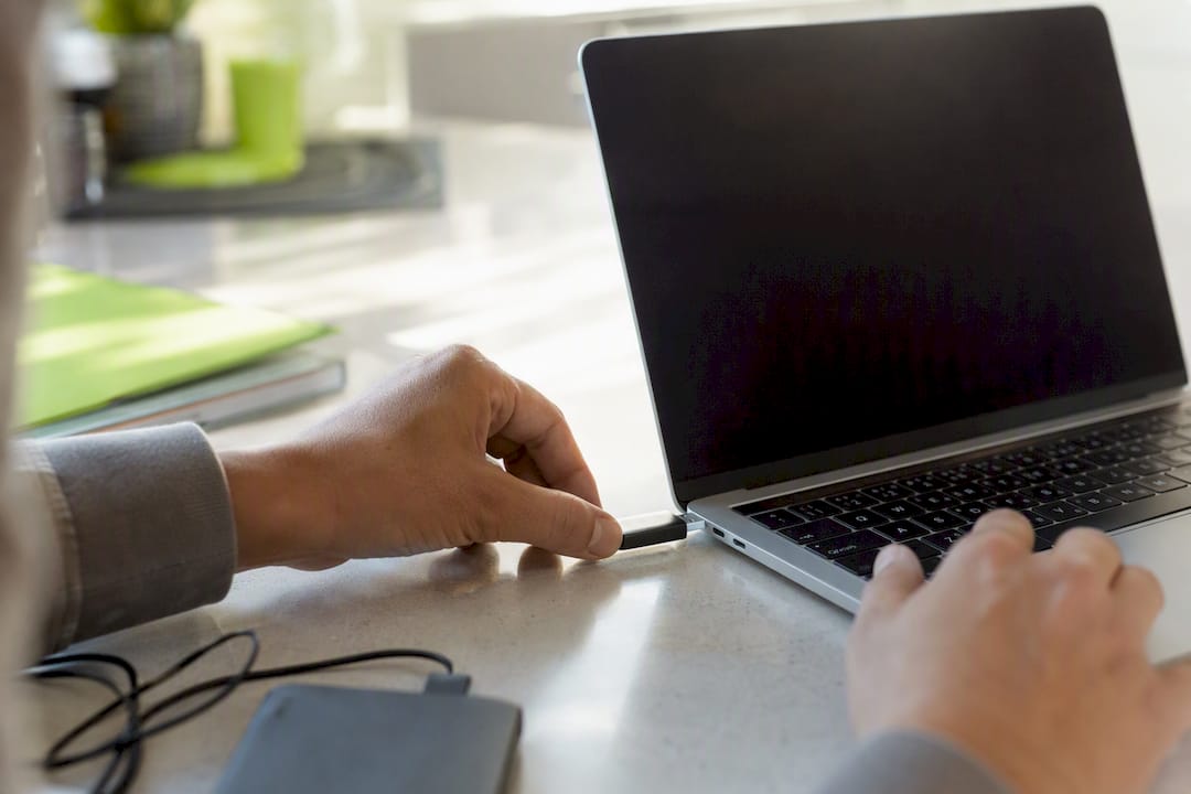 Hands connecting USB drive to laptop