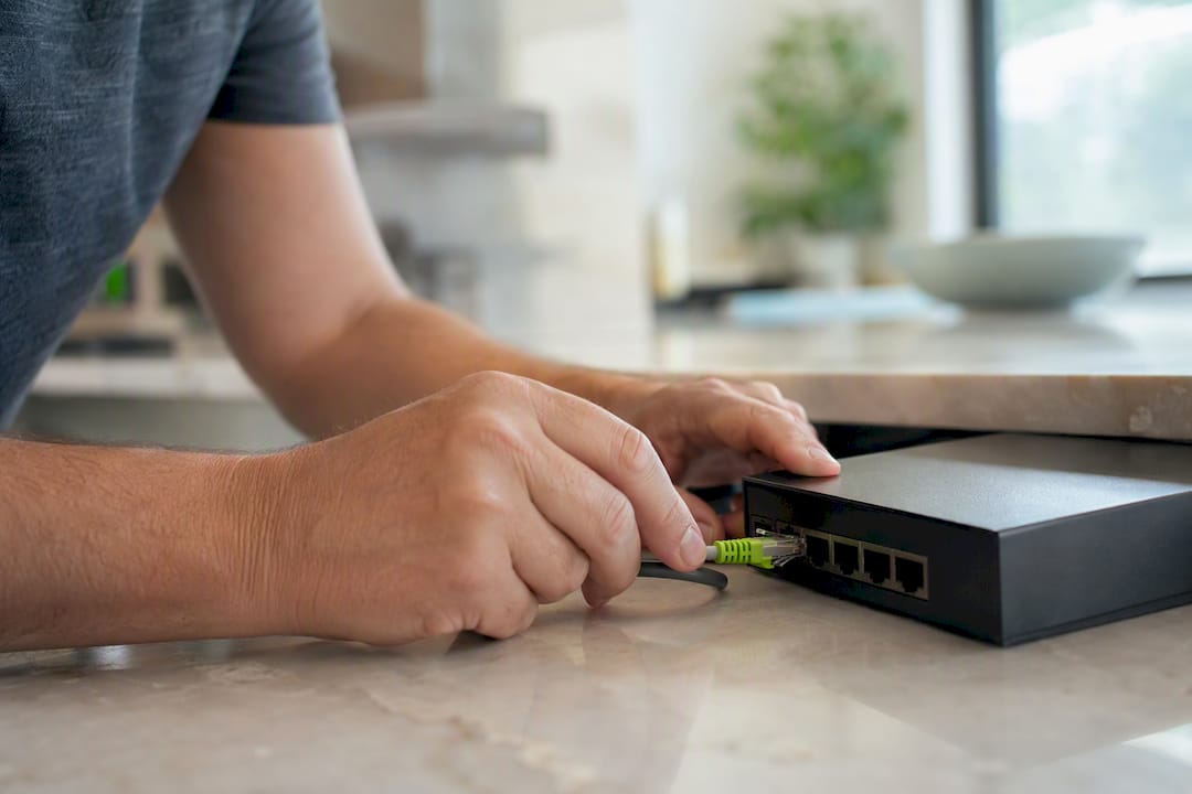 Hands connecting Ethernet cable to network device