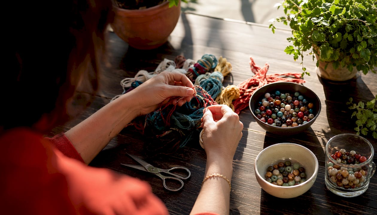 Close-up of hands preparing bracelet making materials